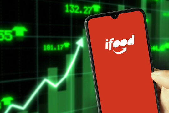 Ifood running on Smartphone with background showing increase value, 25 Apr, 2022, Sao Paulo, Brazil.
