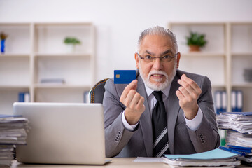 Old male employee holding credit card in the office