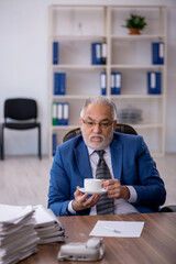 Fototapeta na wymiar Old male employee drinking coffee during break