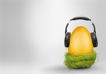 Fresh egg with headphones and cord on gray background. Creative music emotion concept.