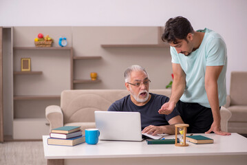 Grandfather and grandson at home with computer