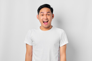 Close up of shocked young Asian man with open mouth and looking at camera isolated on white background
