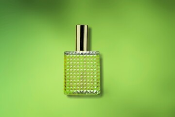 Bottle of perfume with spray on a green bokeh background. Natural  Clear glass.