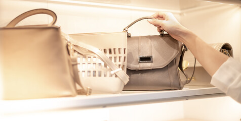 The female hand chooses la eather bag ina  department store.