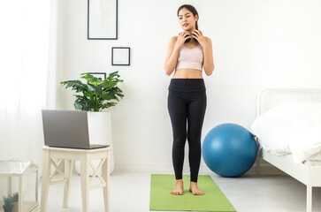 Fototapeta na wymiar Portrait sport asian beauty body slim woman in sportswear sitting relax and girl practicing yoga and do fitness exercise with laptop computer in bedroom at home.Diet concept.Fitness and healthy
