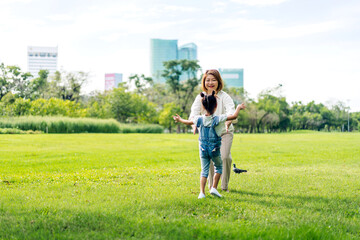 Portrait of happy love asian grandmother and asian little cute girl enjoy relax in summer park.Young girl with their laughing grandparents smiling together.Family and togetherness