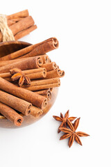 Anise stars and cinnamon sticks in a wooden bowl isolated on white background. Aromatic spices