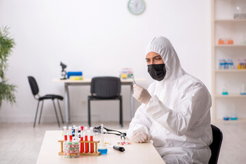 Young male chemist in drugs synthesis concept