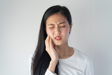 Teeth and gum problem concept. Asian young woman touching cheek and feeling toothache and pain face...