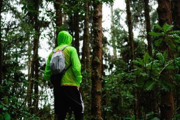 man on his back in the jungle wearing a fluorescent raincoat, contemplating nature. copy space