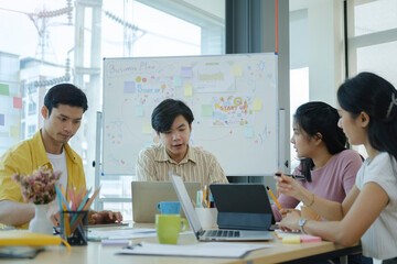 Creative young people sitting around table in modern start up office and working on new project together.