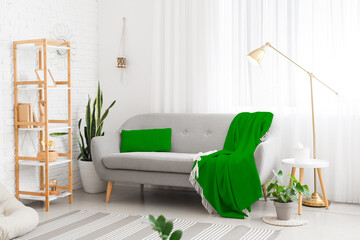 Comfortable sofa, shelf unit, lamp and carpet near window in modern living room interior