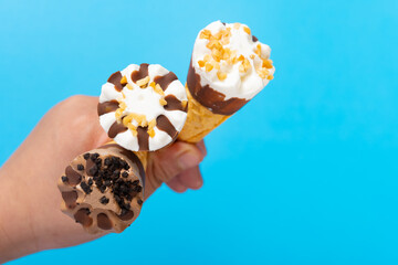 top view kids hand holding three mini size ice cream cones with different flavors on blue - obrazy, fototapety, plakaty