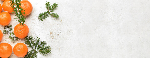Tasty tangerines and fir branches on light background with space for text