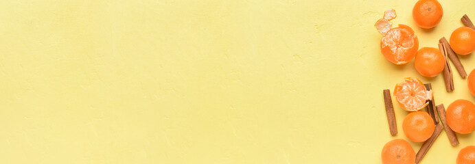 Tasty tangerines and cinnamon sticks on yellow background with space for text