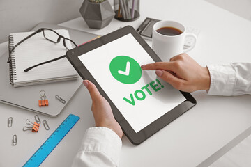 Young woman with tablet computer voting online in office