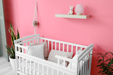 Beautiful crib near color wall in interior of stylish children's room