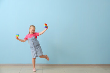 Happy girl with different pop it fidget toys near color wall