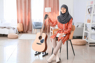 Muslim music teacher with guitar at home