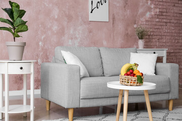 Basket with fruits on table in interior of stylish living room