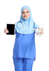 Muslim pediatrician with toy and tablet computer on light background