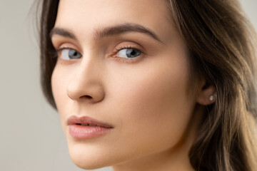 Obraz premium Closeup beauty portrait of beautiful woman with perfect skin, looking at camera with calm expression, wearing casual style jacket. Indoor studio shot isolated on gray background.