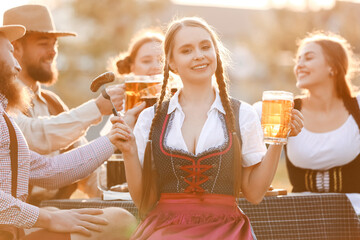 Woman with beer and snack celebrating Octoberfest outdoors