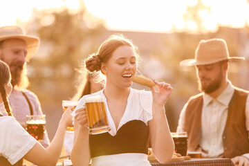 Woman with beer and snack celebrating Octoberfest outdoors