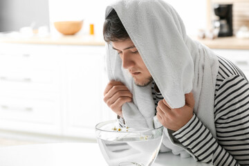 Young man doing steam inhalation at home to soothe and open nasal passages