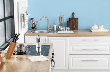 Wooden counters with silver sink and cookware in kitchen