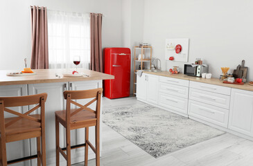 Interior of light kitchen with red fridge, white counters and pegboard