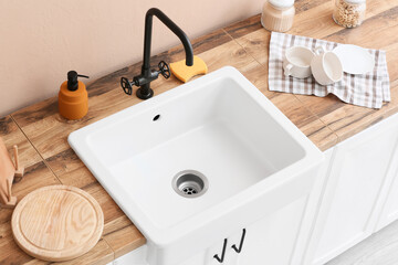 Cleaning sponge with detergent and cups near ceramic sink in kitchen