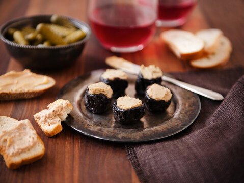 Prunes Stuffed with Foie Gras on a Metal Dish; Bread and Foie Gras; Pickles; Wine.