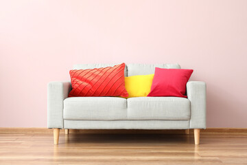 Modern sofa with pillows near color wall in room