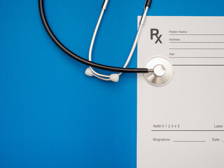 Top view of a stethoscope over the medical prescription sheet on a blue background