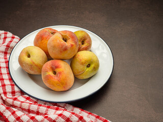 Naklejka na ściany i meble Fresh ripe peaches fruit on a white dish and cloth over the vintage background
