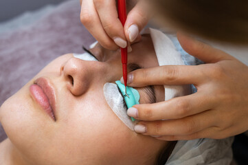 Young woman undergoing eyelash tinting and lamination procedure.