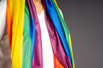 People covering with the rainbow flag or LGBT flag while standing on a gray background