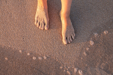 Beach - women's foot and the grains of sand.