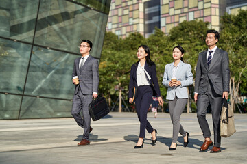 young asian businesspeople walking on street