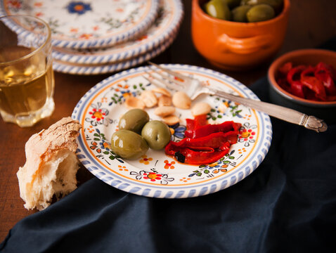 Plate with a Single Serving of Tapas; Green Olives, Roasted Red Peppers and Almonds; Bread and White Wine - Powered by Adobe