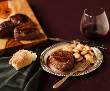 Wagyu Steak and White Beans on a Metal Plate; With Bread and Red Wine
