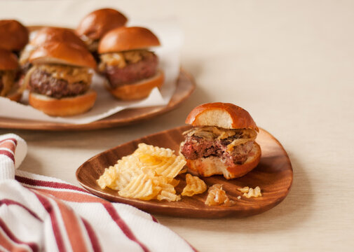 Hamburger Slider with a Bite Taken Out on a Plate with Potato Chips; Platter of Sliders