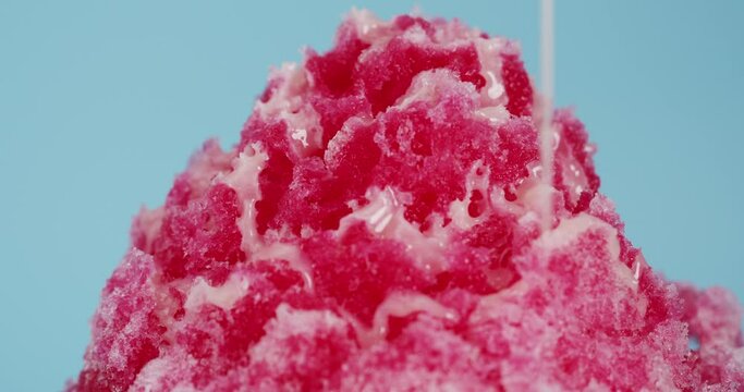 Shaved ice dessert with red juice on top condensed milk.