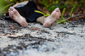 A man lies on the ground in the forest. Possibly murder. Legs without shoes. Soft focus