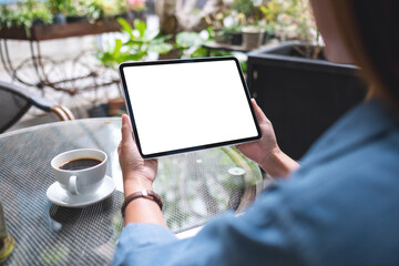 Mockup image of a woman holding digital tablet with blank white desktop screen in the outdoors cafe