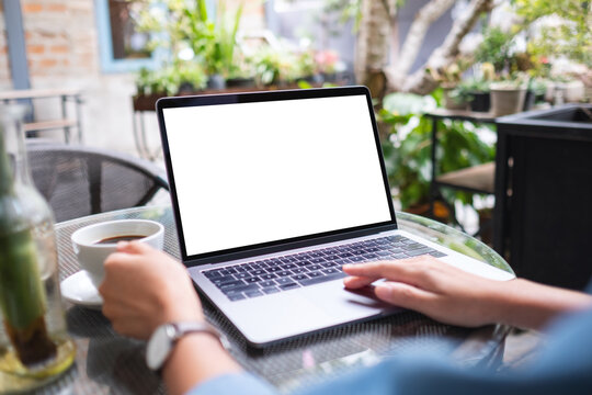Mockup image of a woman using and working on laptop computer with blank white desktop screen while drinking coffee in the outdoors
