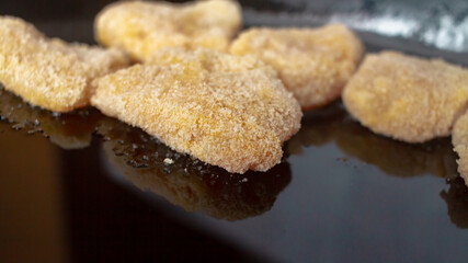 Chicken nuggets in breadcrumbs in a black cast-iron pan for baking