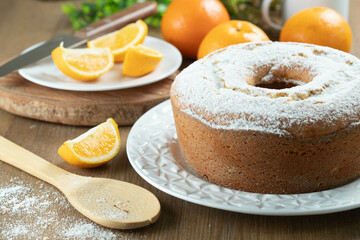 Moist orange fruit cake on plate with orange slices on wooden table. Delicious breakfast, traditional English tea time. Orange cake recipe.