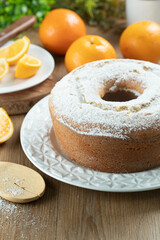 Moist orange fruit cake on plate with orange slices on wooden table. Delicious breakfast, traditional English tea time. Orange cake recipe.